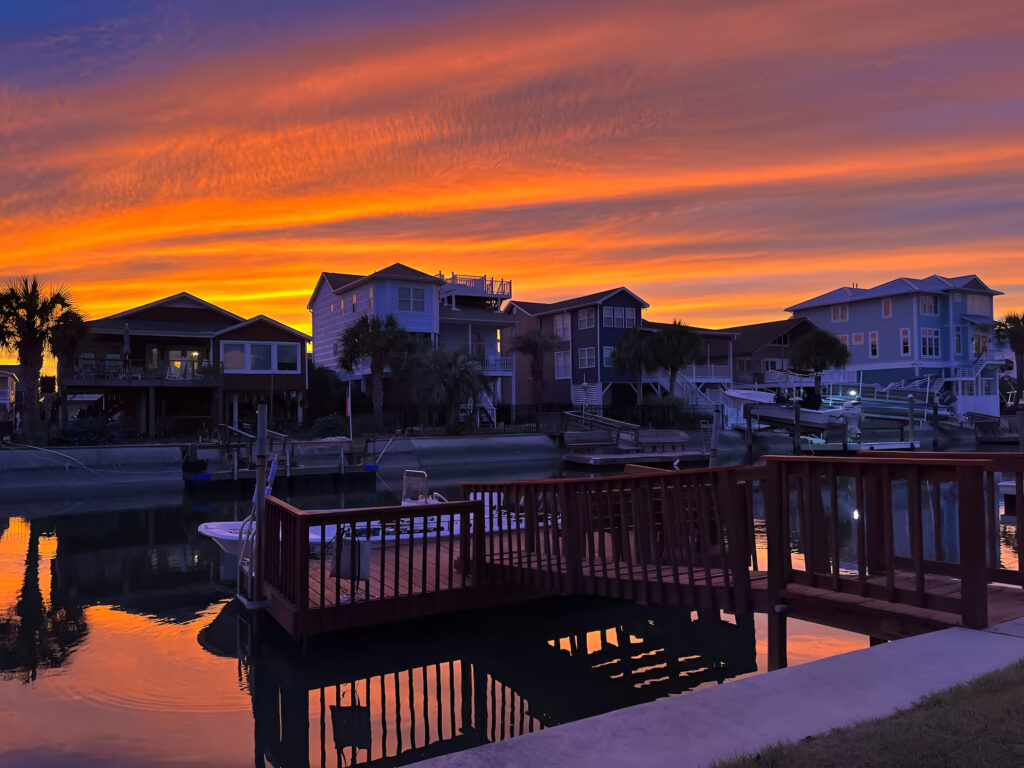 Sunset view of a boat docked on the canal at a waterfront vacation rental in Ocean Isle Beach