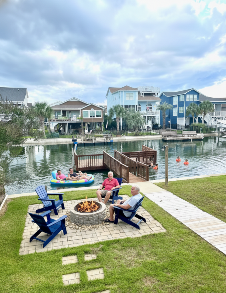 Multigenerational family enjoying a waterfront fire pit and swimming in the canal at an Ocean Isle Beach vacation home
